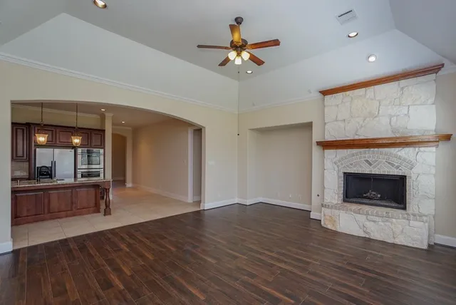 a view of an empty room with wooden floor fireplace and a window