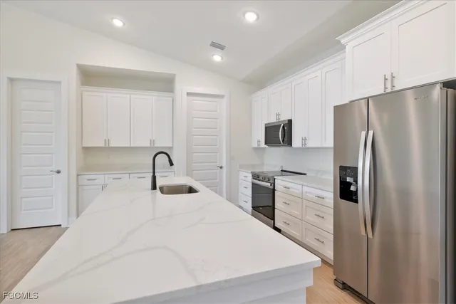 a kitchen with stainless steel appliances a refrigerator sink and white cabinets