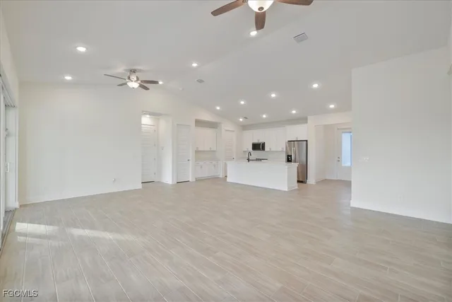 a view of an empty room with a ceiling fan kitchen appliances and a ceiling fan