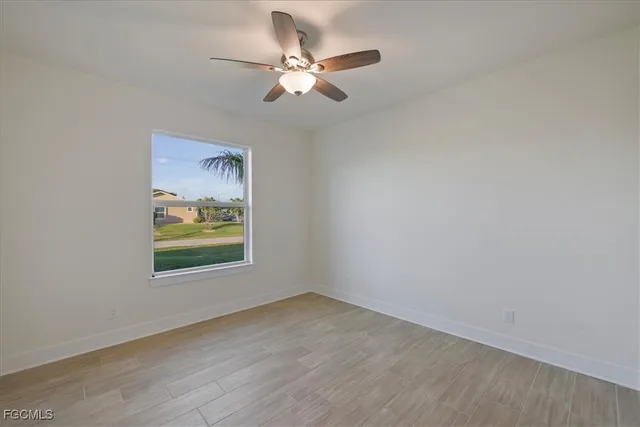 an empty room with window and ceiling fan