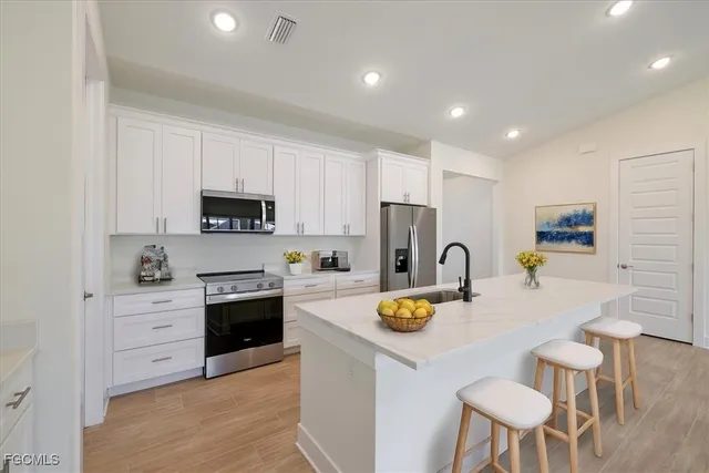a kitchen with a refrigerator a stove a sink and chairs