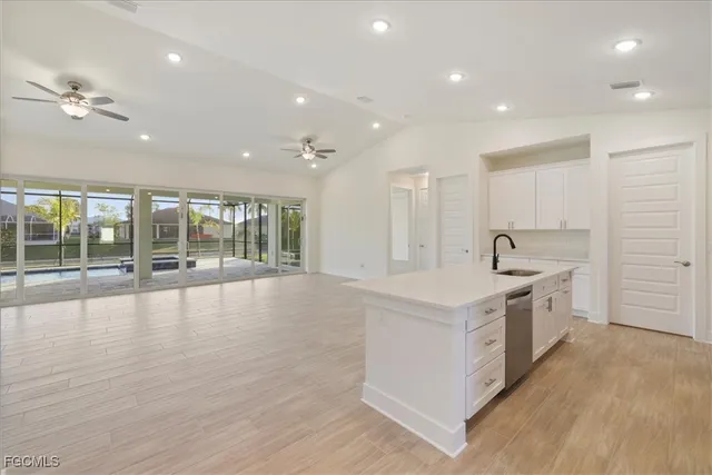 a large kitchen with stainless steel appliances a large counter top a stove and a wooden floors