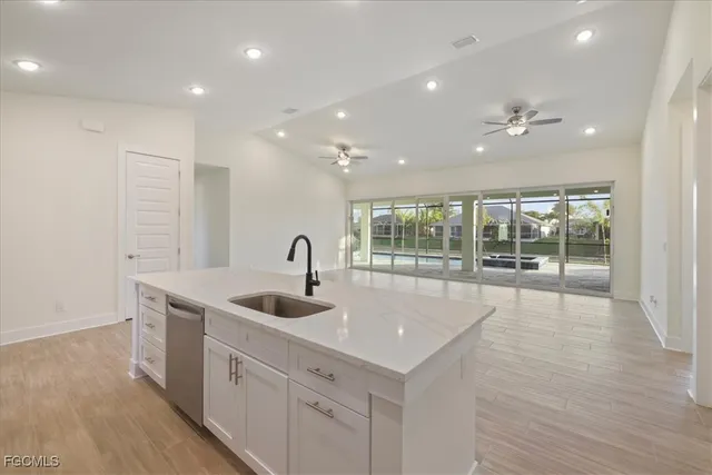 a large kitchen with sink and dishwasher with wooden floor