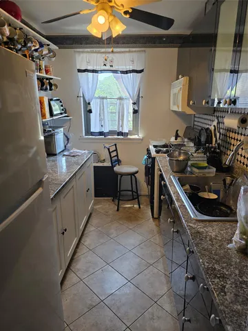 a kitchen with granite countertop a sink a stove and a refrigerator