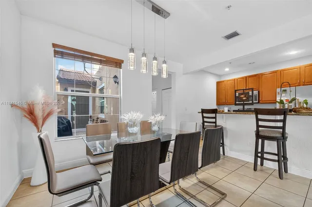 a dining room with stainless steel appliances kitchen island granite countertop a table chairs and a glass top table
