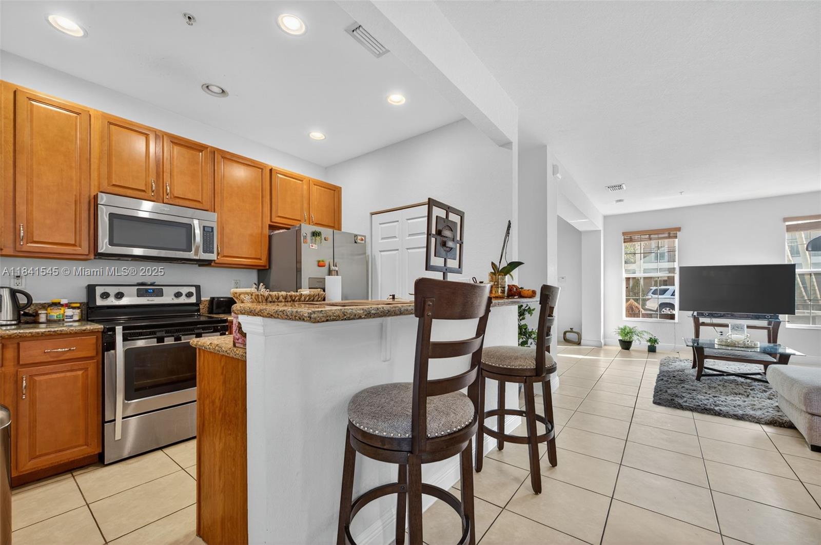 14615 Southwest 14 Street, Unit 14615 Pembroke Pines, FL 33027 - Photo 17 of 49 a kitchen with stainless steel appliances granite countertop a stove top oven a sink a dining table and chairs