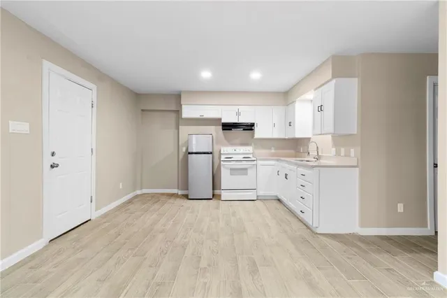 a kitchen with white cabinets appliances and wooden floor