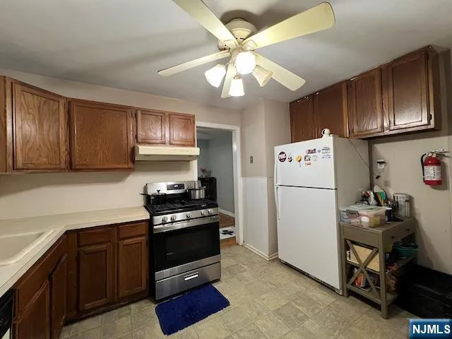 a kitchen with granite countertop a refrigerator a stove a sink and cabinets