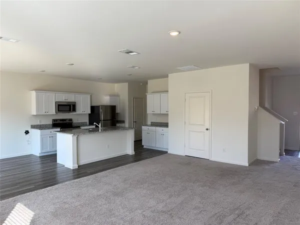 a kitchen with stainless steel appliances granite countertop a refrigerator a stove and a wooden floors