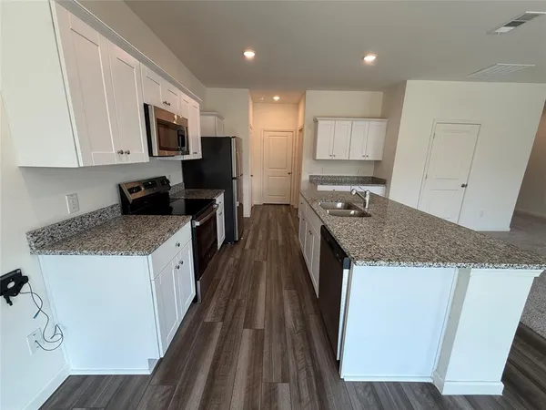 a living room with stainless steel appliances kitchen island sink refrigerator and a fireplace