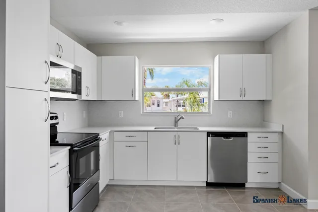 a kitchen with cabinets appliances a sink and a window