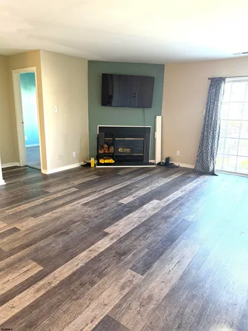 a view of an empty room with wooden floor and a fireplace