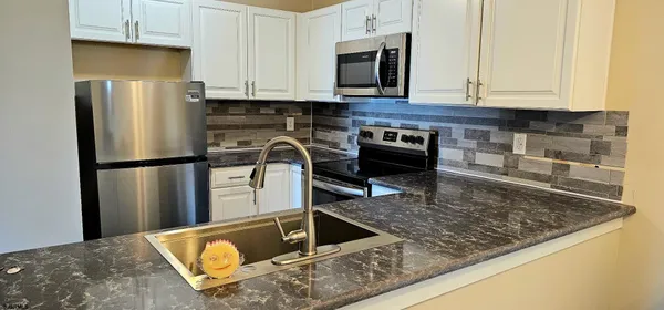 a kitchen with stainless steel appliances granite countertop a refrigerator a stove and a sink