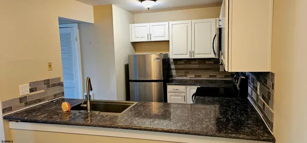 a kitchen with kitchen island granite countertop a refrigerator a stove and a sink