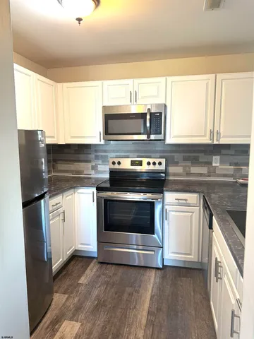 a kitchen with granite countertop a stove top oven microwave and refrigerator