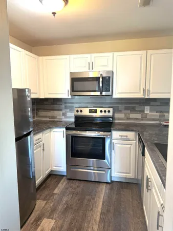 a kitchen with granite countertop a stove top oven microwave and refrigerator