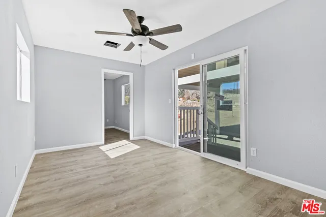 a view of a room with wooden floor and a ceiling fan