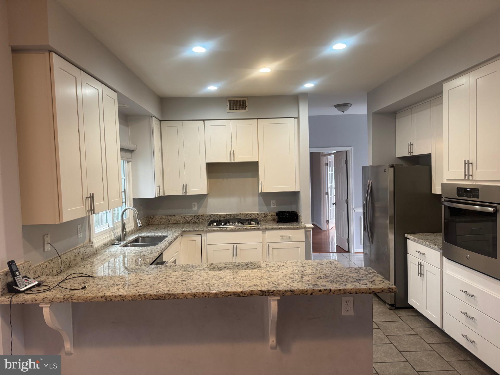 8143 Ridge Creek Way Springfield, VA 22153 - Photo 8 of 42 a kitchen with stainless steel appliances granite countertop a sink a stove and a refrigerator