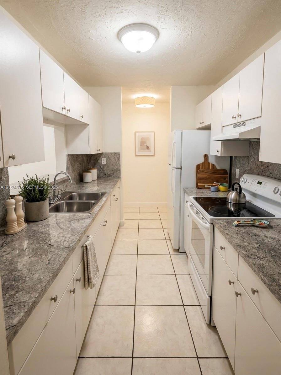 2725 West Okeechobee Road, Unit 17 Hialeah, FL 33010 - Photo 2 of 4 a kitchen with a sink a stove and cabinets