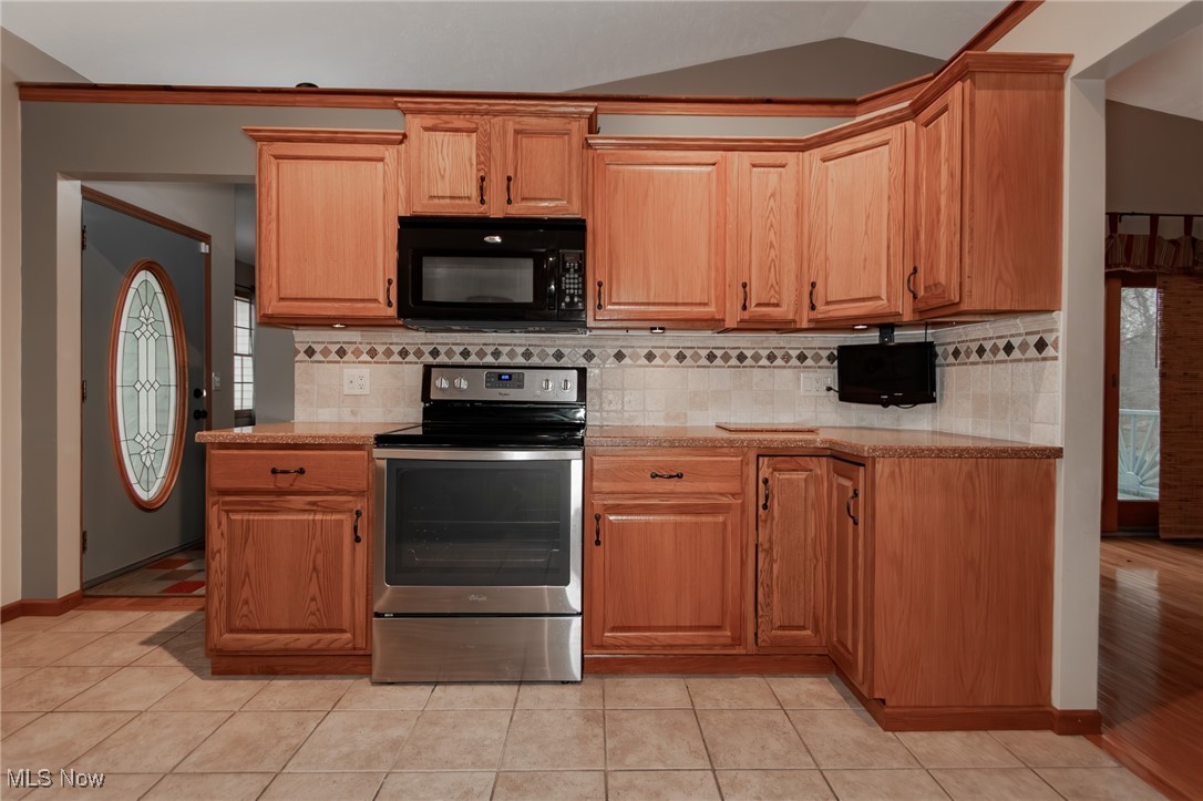 4815 South Ridge Road Perry, OH 44081 - Photo 11 of 48 Kitchen featuring electric stove, black microwave, lofted ceiling, light tile patterned floors, and backsplash