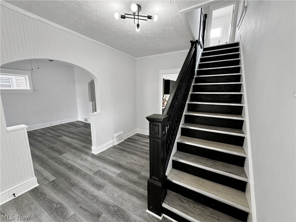 977 Nathaniel Road Cleveland, OH 44110 - Photo 5 of 22 Staircase featuring dark risers and light wood-finish treads, complemented by a dark wood newel post and balustrade