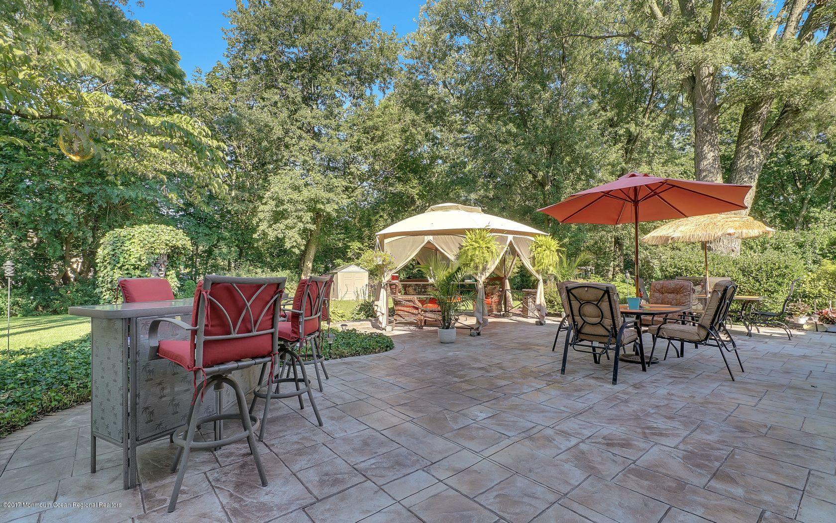 9 Cornwall Road Freehold, NJ 07728 - Photo 35 of 38 a view of a tables and chairs under an umbrella in backyard