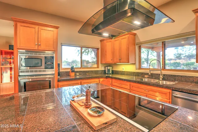 a kitchen with stainless steel appliances granite countertop a sink a stove and a refrigerator