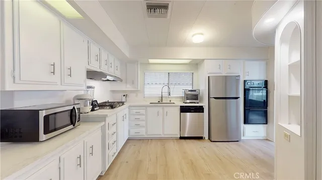 a kitchen with white cabinets and stainless steel appliances