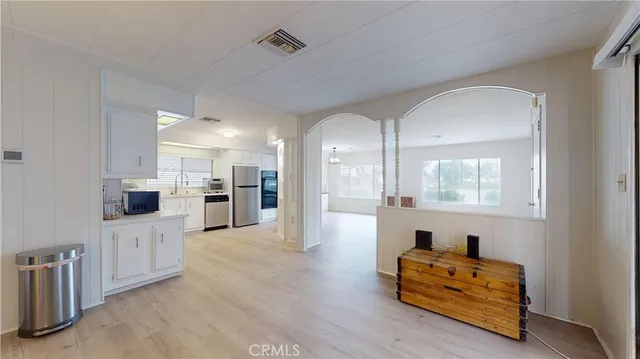 a living room with furniture kitchen view and a wooden floor
