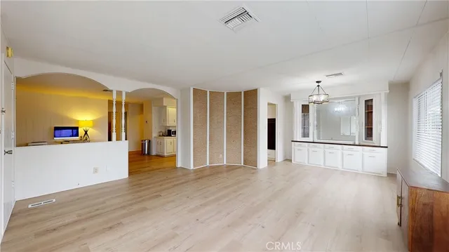 a view of an empty room with window and wooden floor