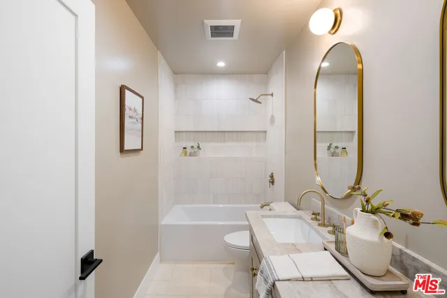 a bathroom with double vanity sinks a toilet and a mirror