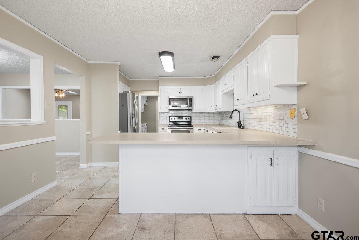 15938 Big Oak Bay Road Tyler, TX 75707 - Photo 7 of 21 a kitchen with stainless steel appliances a sink a stove a refrigerator cabinets and a window