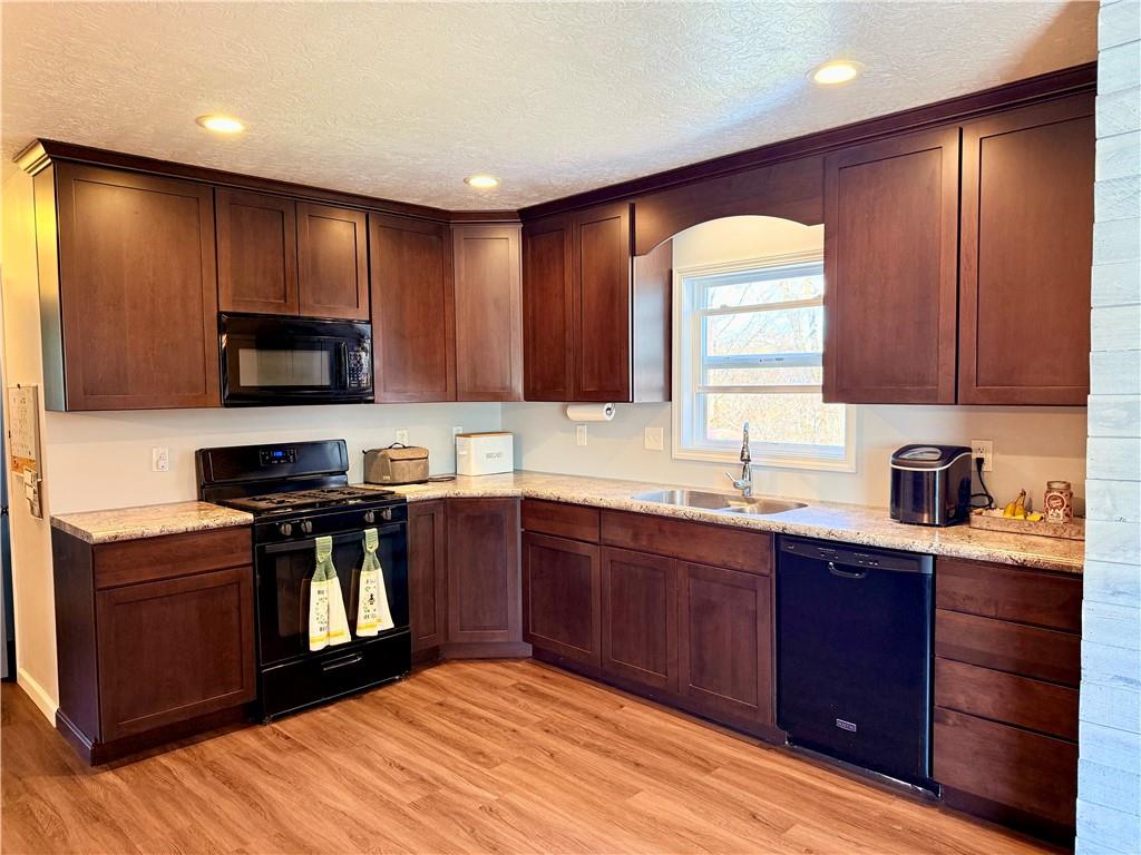 2459 Doc Walker Road Parker, PA 16049 - Photo 4 of 18 a kitchen with stainless steel appliances granite countertop wooden cabinets a stove top oven a sink and dishwasher with wooden floor