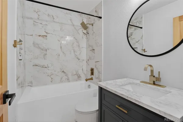 a bathroom with a granite countertop sink a toilet and a mirror