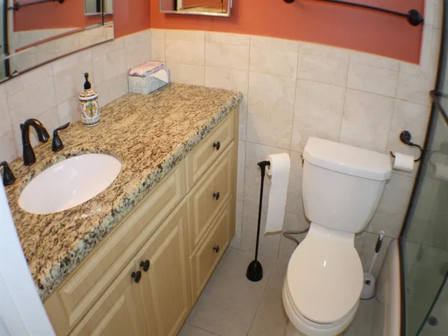 a bathroom with a granite countertop toilet and a sink