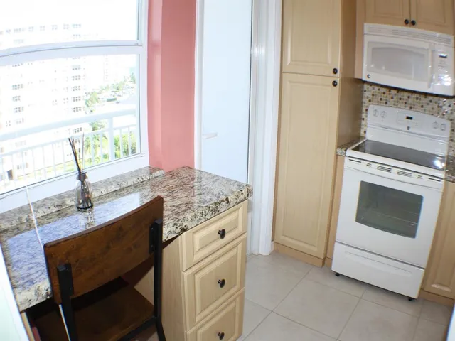 a kitchen with granite countertop cabinets stainless steel appliances a sink and a window
