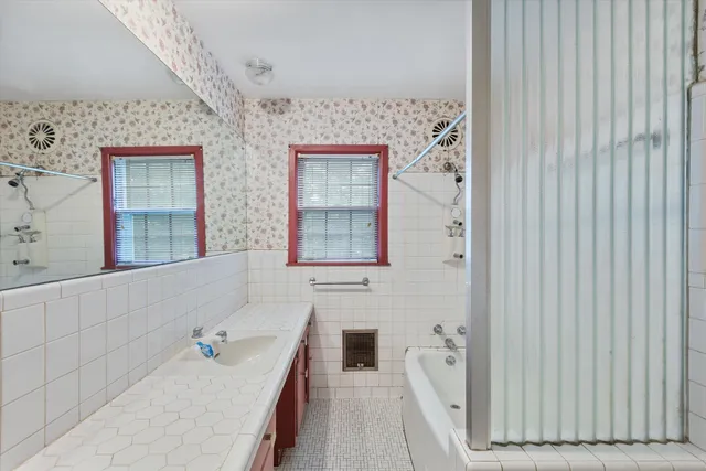 a bathroom with a tub sink and mirror
