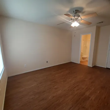 an empty room with a chandelier fan and windows