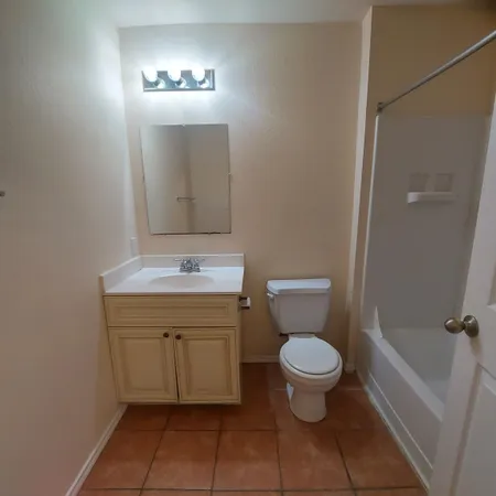 a bathroom with a granite countertop toilet a sink and a mirror