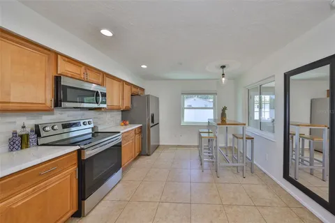 a open kitchen with stainless steel appliances granite countertop a stove top oven a sink dishwasher a dining table and chairs with wooden floor