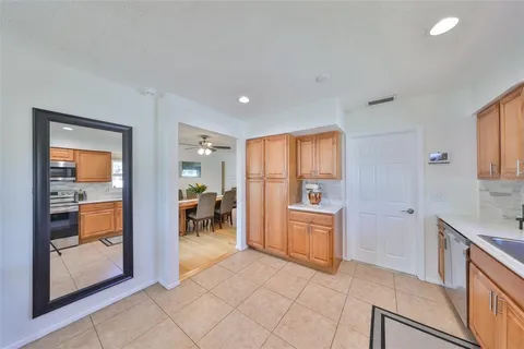 a view of a kitchen with granite countertop a refrigerator a sink a dining table and chairs