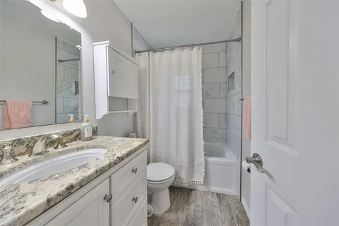 a bathroom with a granite countertop sink a toilet a mirror and shower