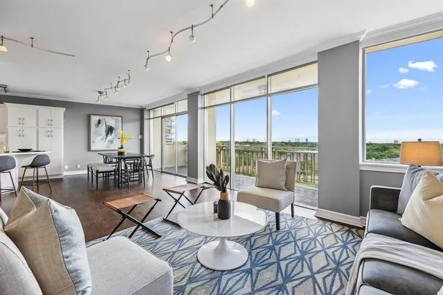 a living room with furniture large windows and wooden floor