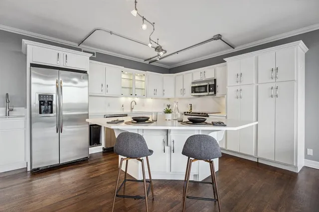 a kitchen with stainless steel appliances granite countertop a refrigerator a stove a sink dishwasher a dining table and chairs with wooden floor