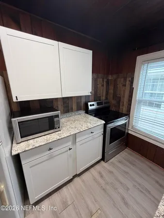 a kitchen with granite countertop a stove a sink and a microwave