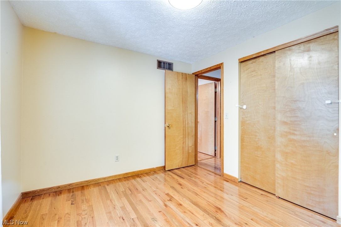 5303 Laubert Road Atwater, OH 44201 - Photo 21 of 37 Unfurnished bedroom featuring light hardwood / wood-style floors, a closet, and a textured ceiling