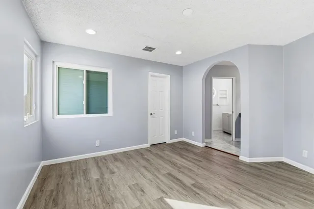 an empty room with wooden floor and windows
