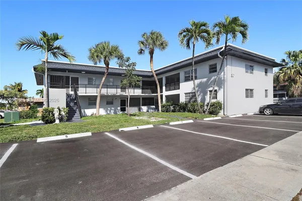 a view of a house with a yard and palm trees
