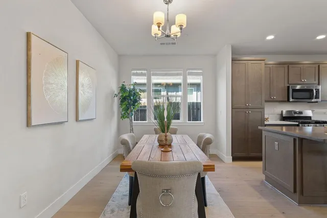a dining room with wooden floor a chandelier a wooden table and chairs