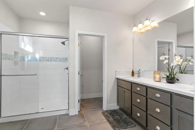 a bathroom with a double vanity sink mirror and shower